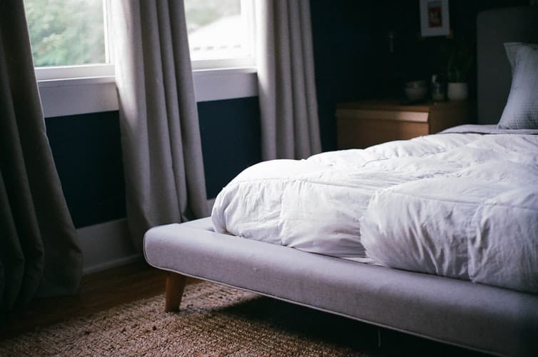 The edge of a bed with a mattress.