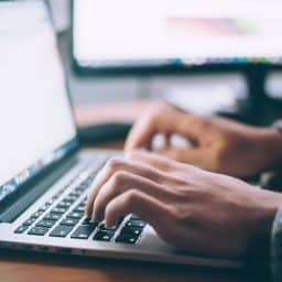 A close-up of hands typing on a laptop keyboard.