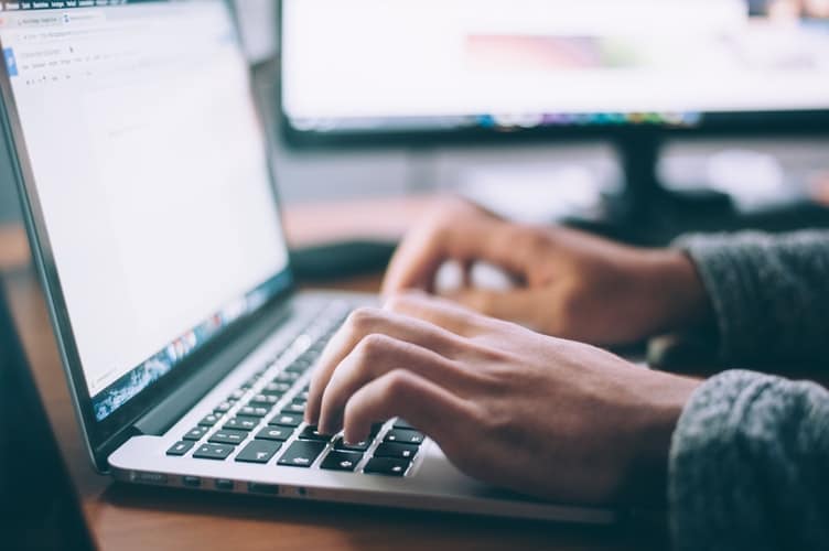 A close-up of hands typing on a laptop keyboard.