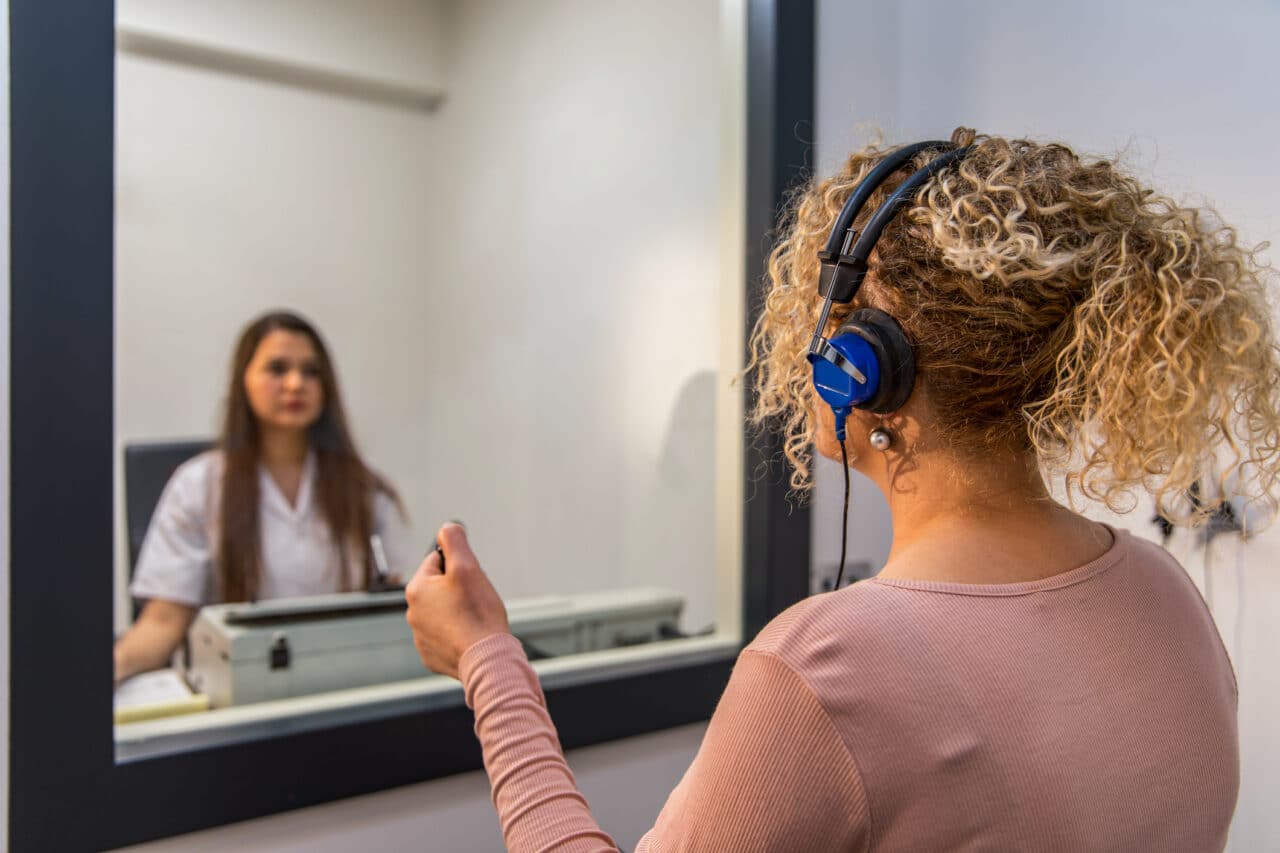 A woman with headphones getting a hearing test at an audiologist's office.