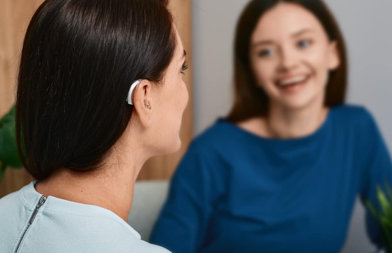 Younger woman with hearing aid talking to her friend.