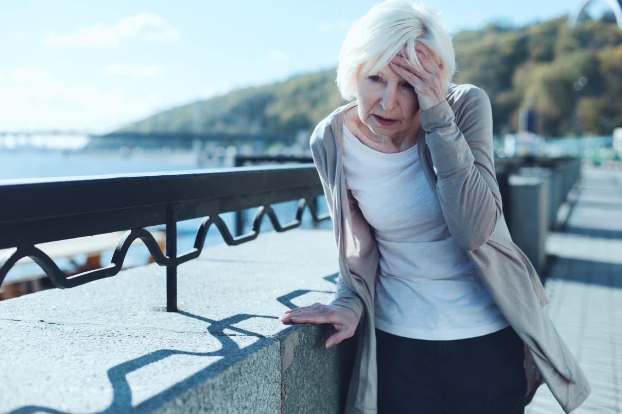 Senior woman feeling dizzy while walking outside.