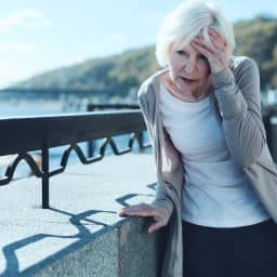 Senior woman feeling dizzy while walking outside.