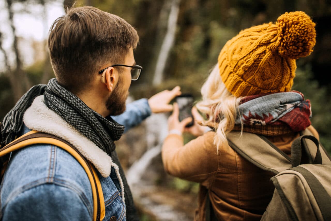 A young couple hiking in the mountains. Man is wearing hearing aids.