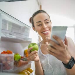 Woman selects apple from refrigerator