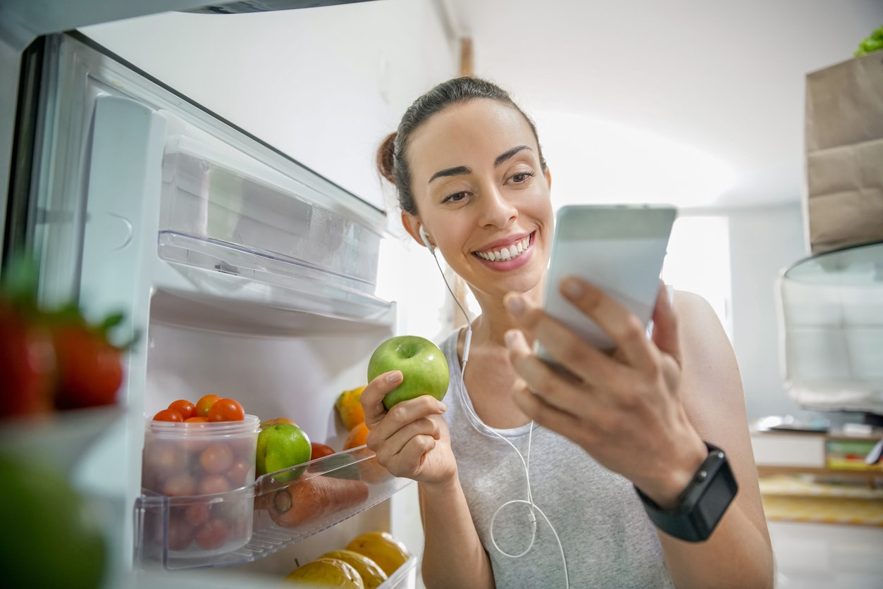 Woman selects apple from refrigerator