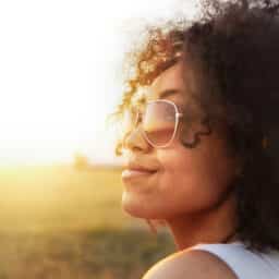 Happy woman with sunglasses sitting in the sun