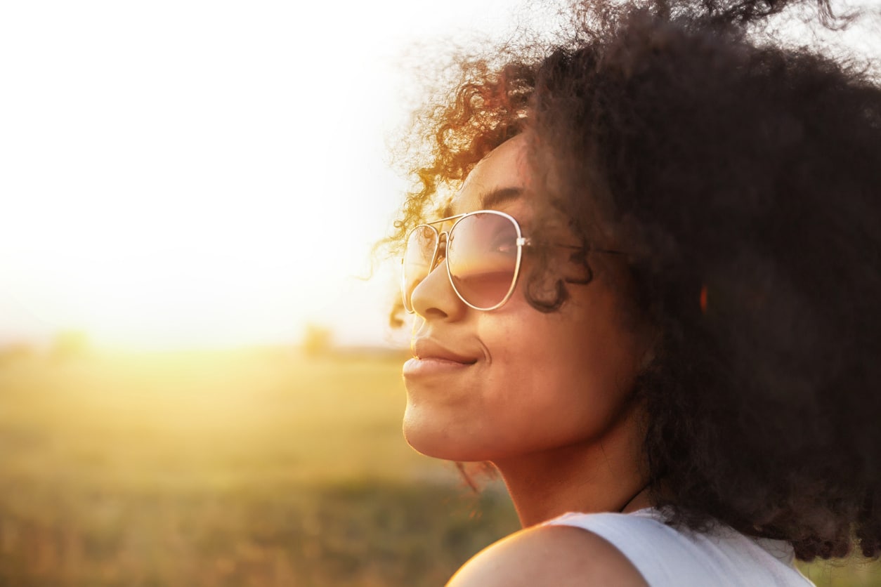 Happy woman with sunglasses sitting in the sun.