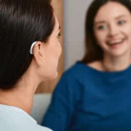 Woman wearing a hearing aid talking to her friend.