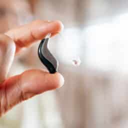 Close-up of a senior hand holding a modern hearing aid device