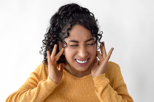 Woman with tinnitus holding her ears.